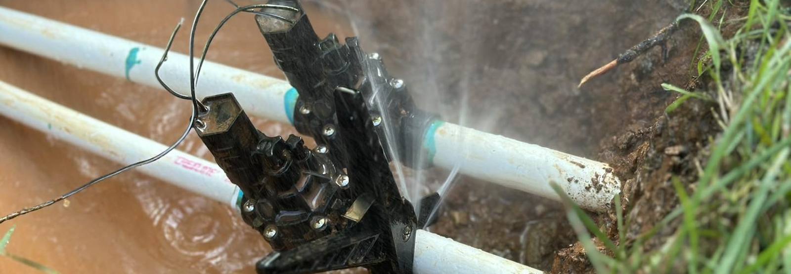 Close-up of irrigation pipe trenching with water spray