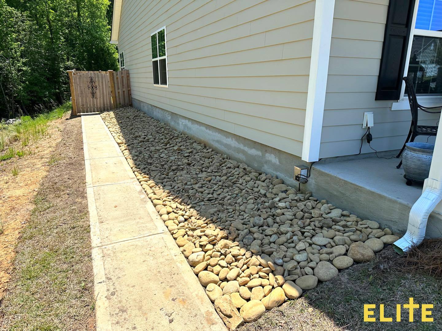 Stone drainage bed installed alongside home foundation