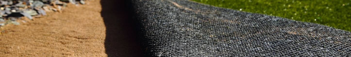 Laying artificial grass turf onto sand in a back garden yard