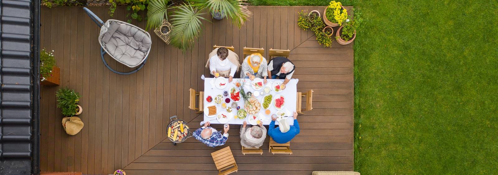 Group of older friends sitting by the table at the party at the terrace