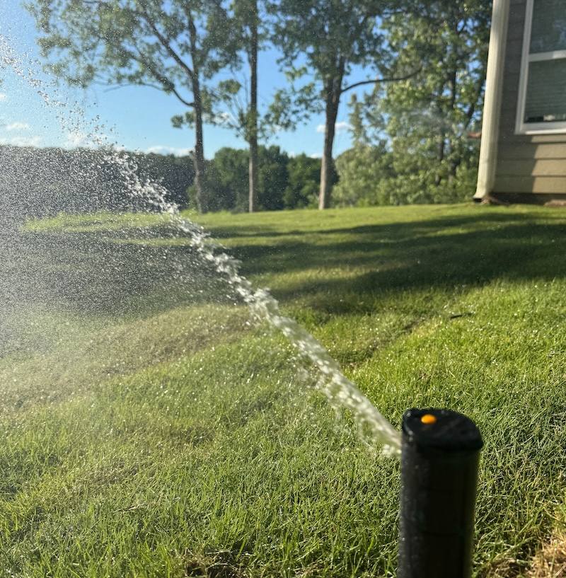 Sprinkler system watering sloped backyard lawn