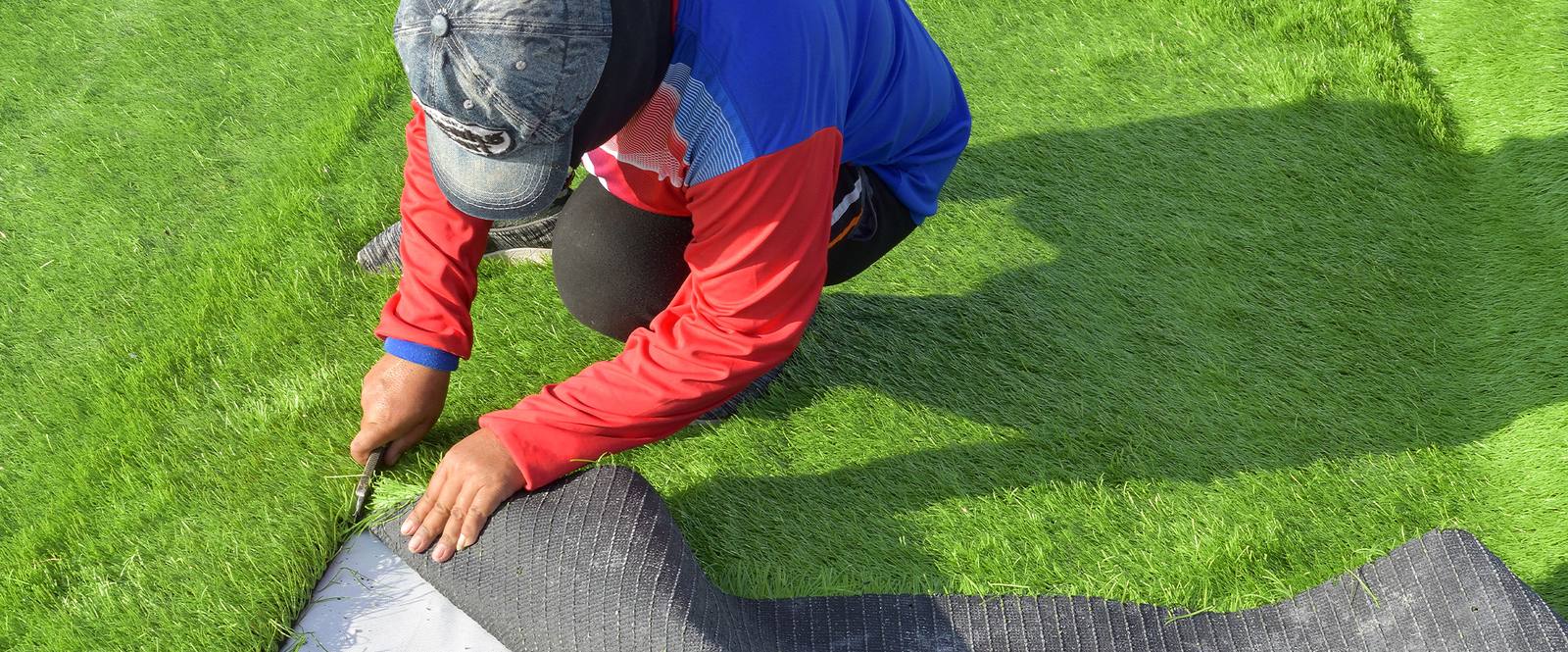Worker installing artificial turf on lawn