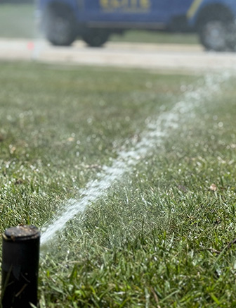 Sprinkler system watering freshly cut green grass